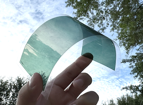Hand holding translucent green curved plastic film