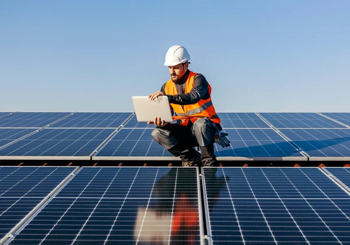 Technician inspecting solar panels with laptop